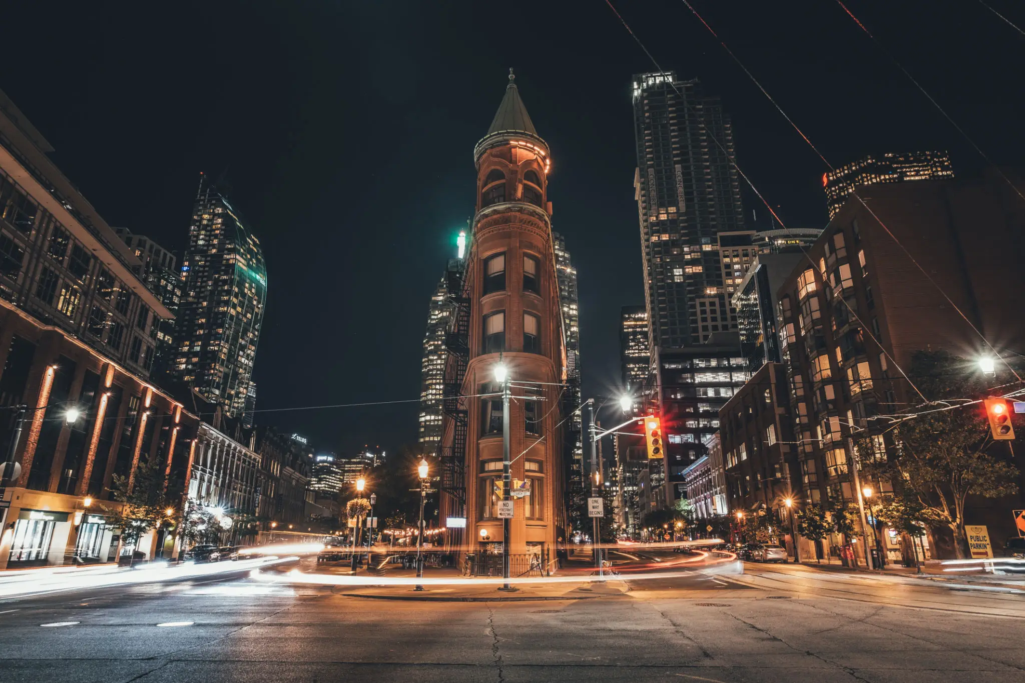 City intersection with tall, narrow building at night.