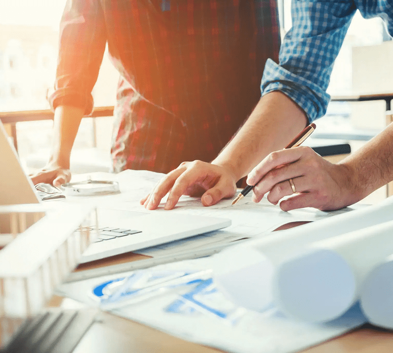 People collaborating on architectural plans in office.